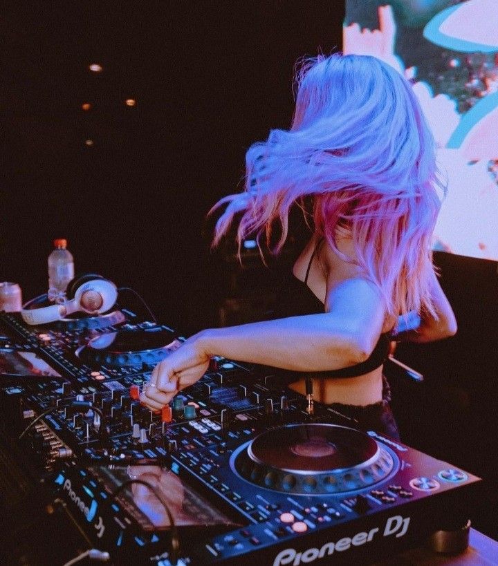 DJ-ka za Pioneer mešalno mizo pod modro in roza klubsko svetlobo